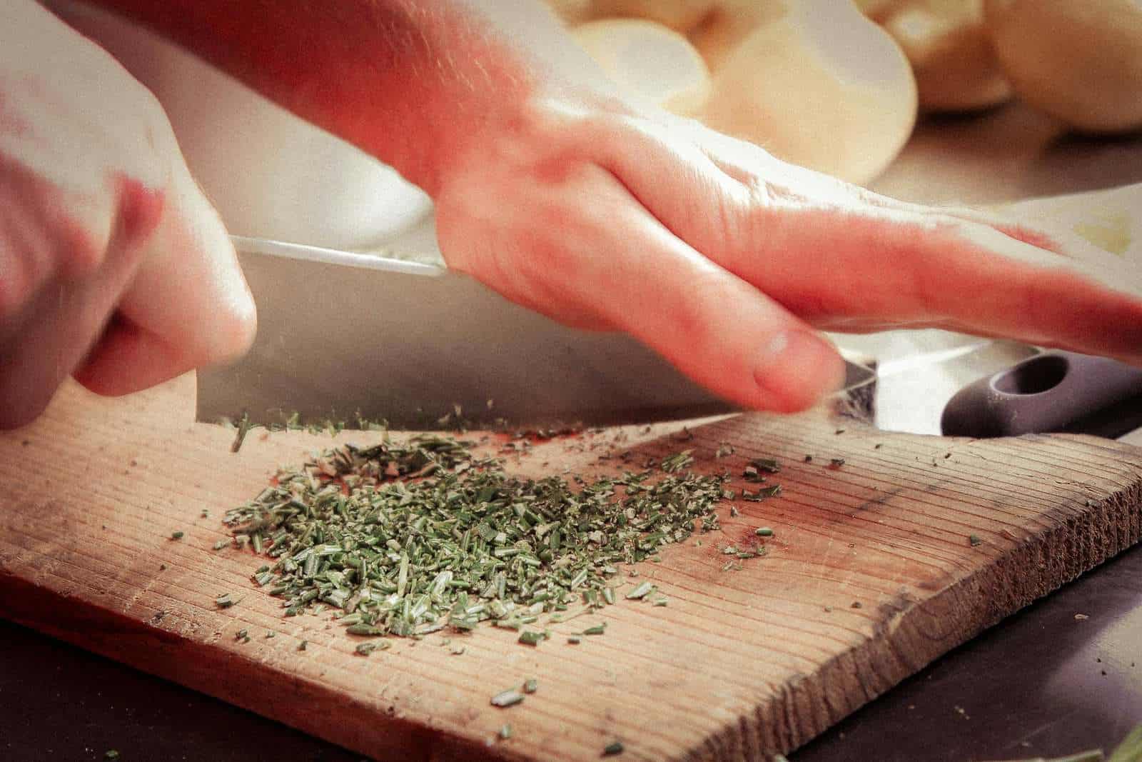 Best Strains for Cooking with Cannabis 1 A person cutting herbs on a cutting board.